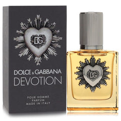 Dolce & Gabbana Devotion Pour Homme perfume bottle with amber liquid and a silver heart emblem, shown next to its dark gray packaging box with matching heart design.