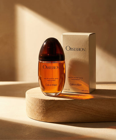Calvin Klein Obsession perfume bottle and packaging on a wooden platform with a neutral background