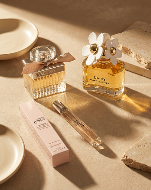 Two perfume bottles on a beige surface with soft shadows