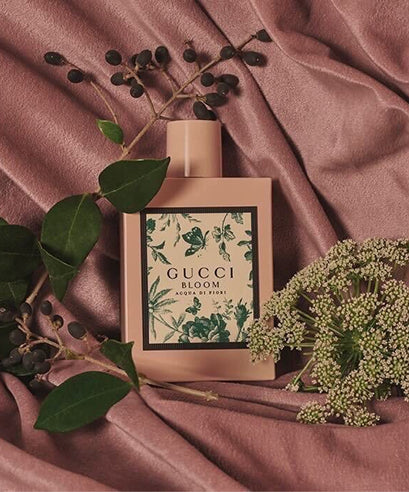 Gucci Bloom perfume bottle with floral design on a pink fabric background